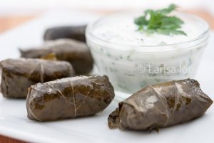 Dolma(tolma, sarma) in grape leaves with meat served with sauce from yogurt and greens.