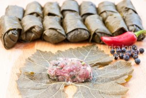 cooking of dolma from pickled grape leaves, minced meat and rice with jalapeno pepper on the wooden board close up