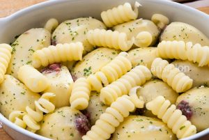 Raw potatoes stuffed with minced meat in a baking dish closeup.