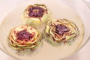 Artichokes hearts in a glass bowl with water closeup.