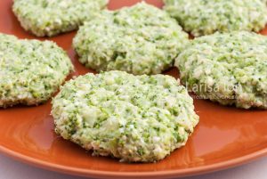 Raw broccoli and cheese pancakes on a brown plate closeup.