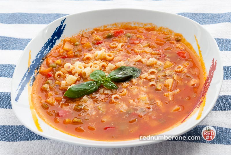 Minestrone soup with grated parmesan cheese and basil leaves